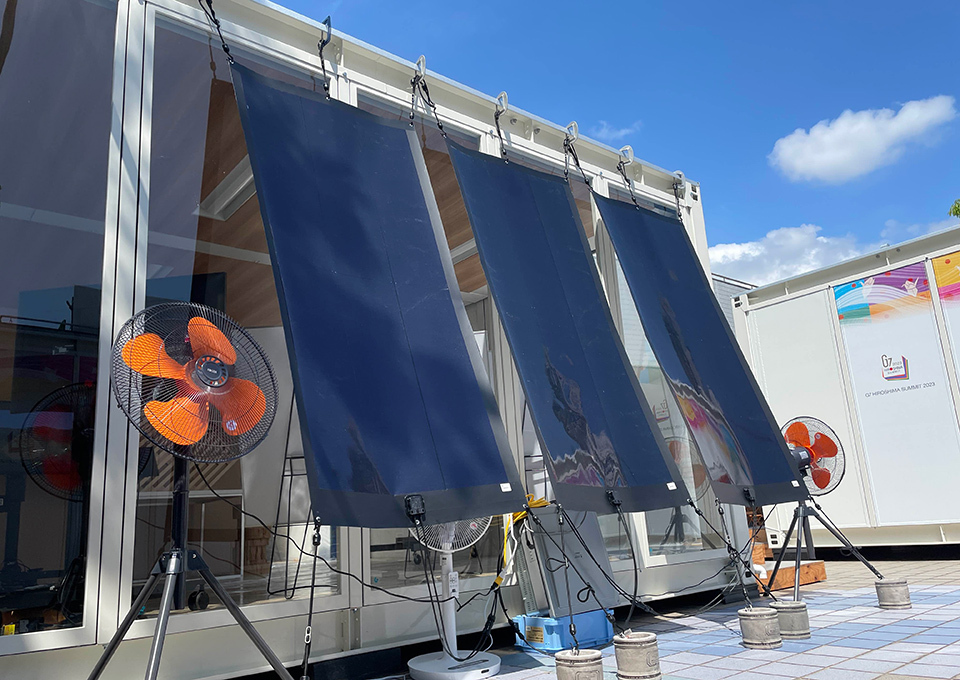 Film-like solar cells being stretched from the eaves of a building like sunshades.