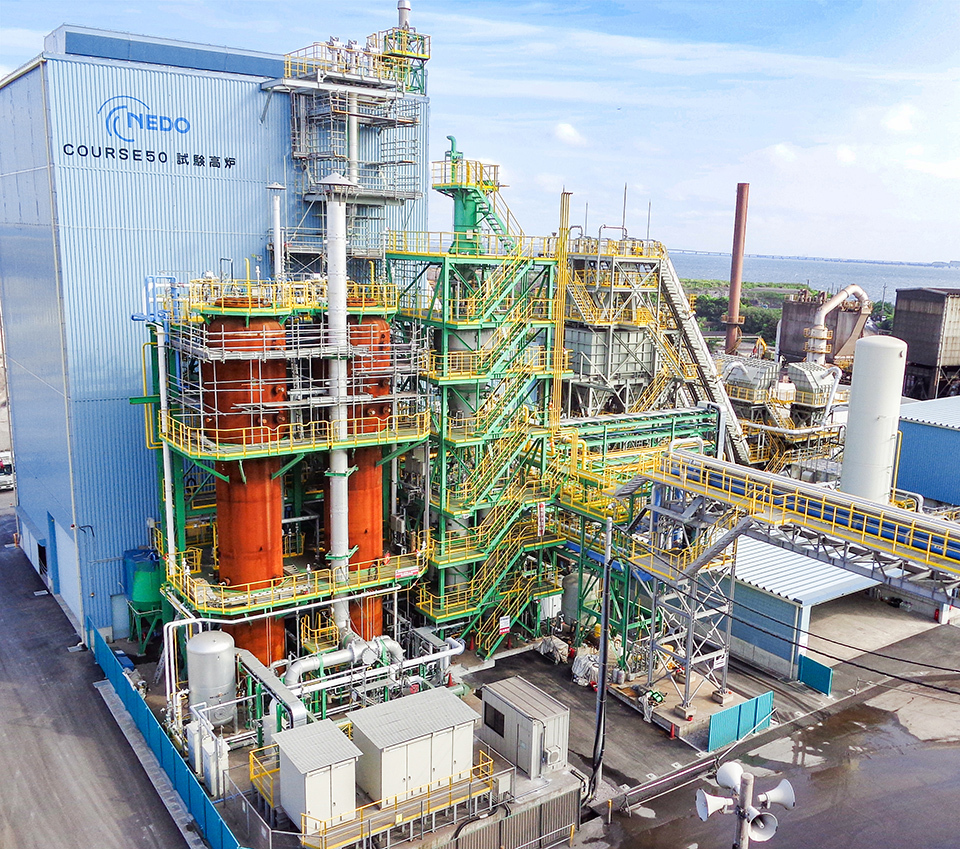 It's visible various pipes and machinery, and ‘NEDO’ logo at the top left corner of the blue furnace.