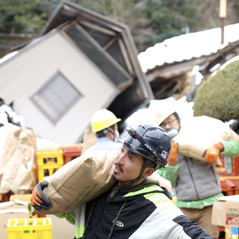 Diverse volunteers carrying a bag of rice on their shoulders.