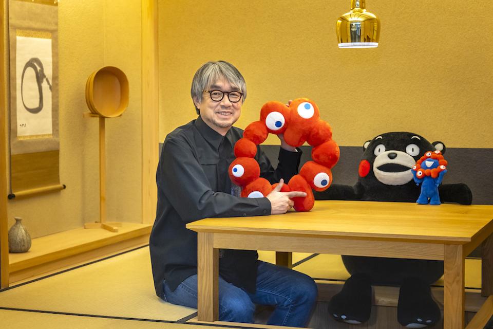 A man sitting at a table above a recessed floor for legroom with tatami, clutching a red toy.