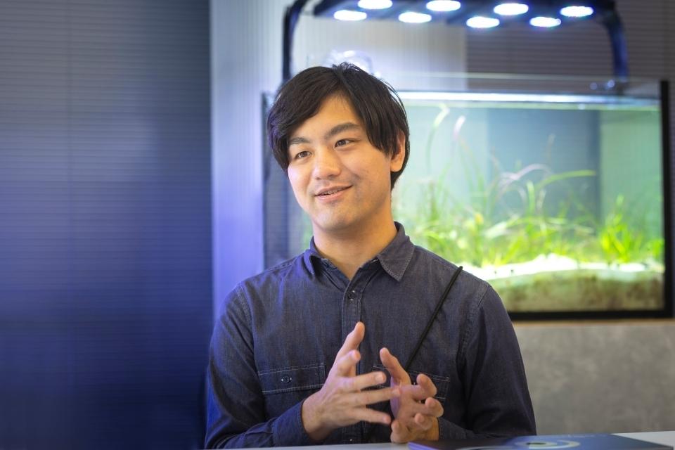Innoqua Inc.'s COO, TAKEUCHI Shiki, with an aquarium in the background.
