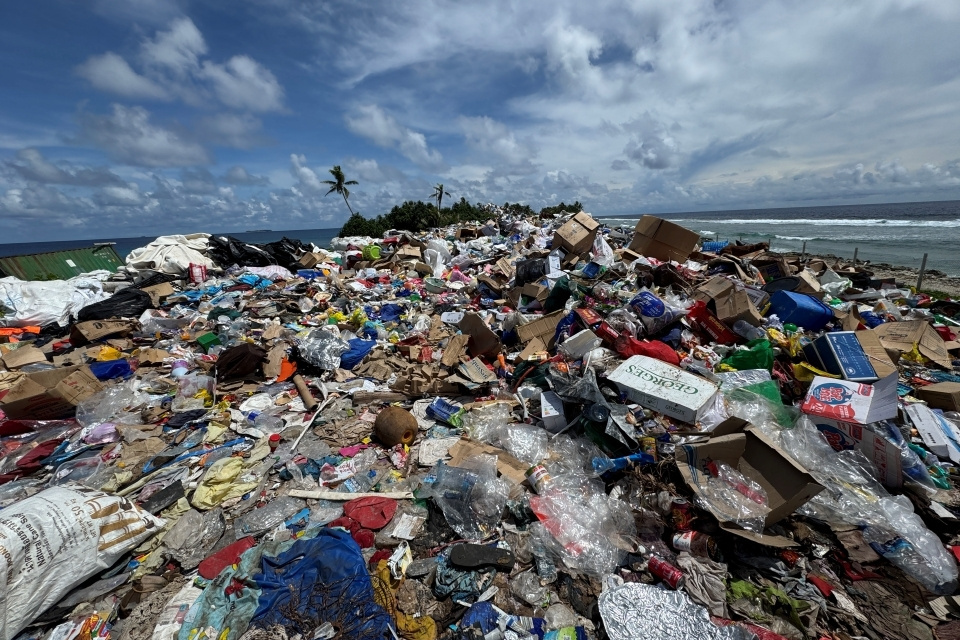 A landfill heaped with garbage of various types, under a blue sky scattered with clouds