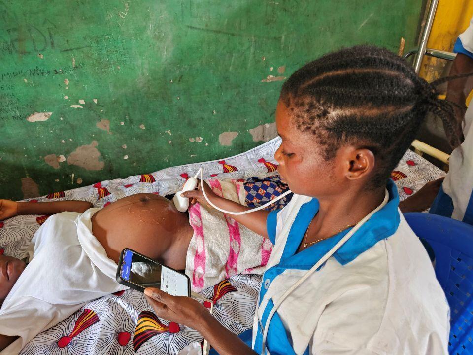 A woman in Sub-Saharan Africa using a portable sonograph connected to a smartphone during a maternal wellness check