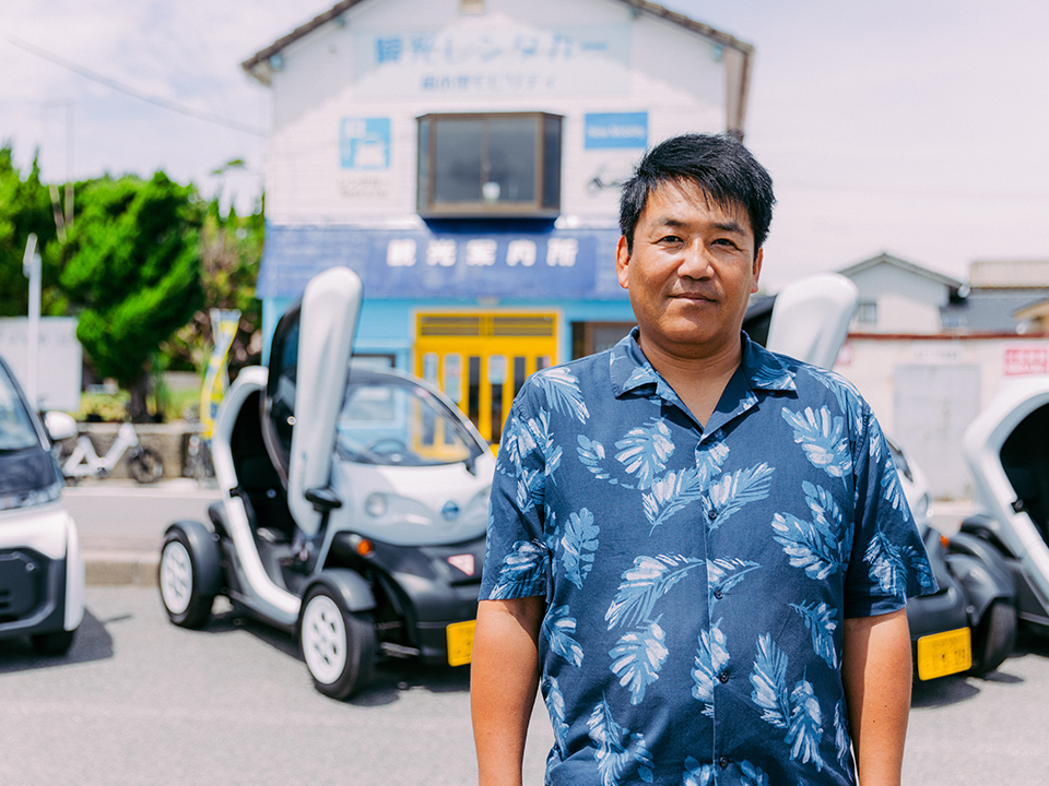 Terashita Mitsuru posing in front of several EVs