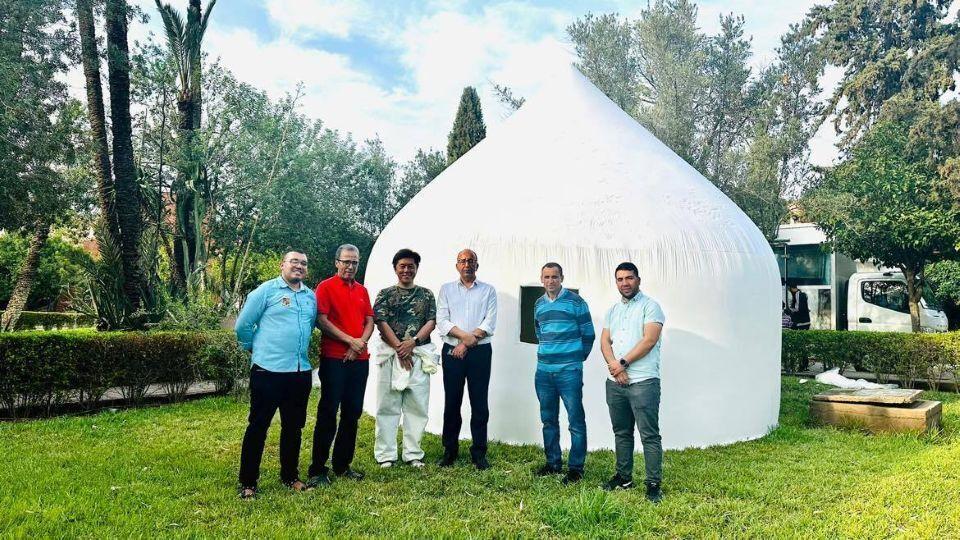 Six people standing in front of an Instant House erected in Morocco after the September 2023 earthquake