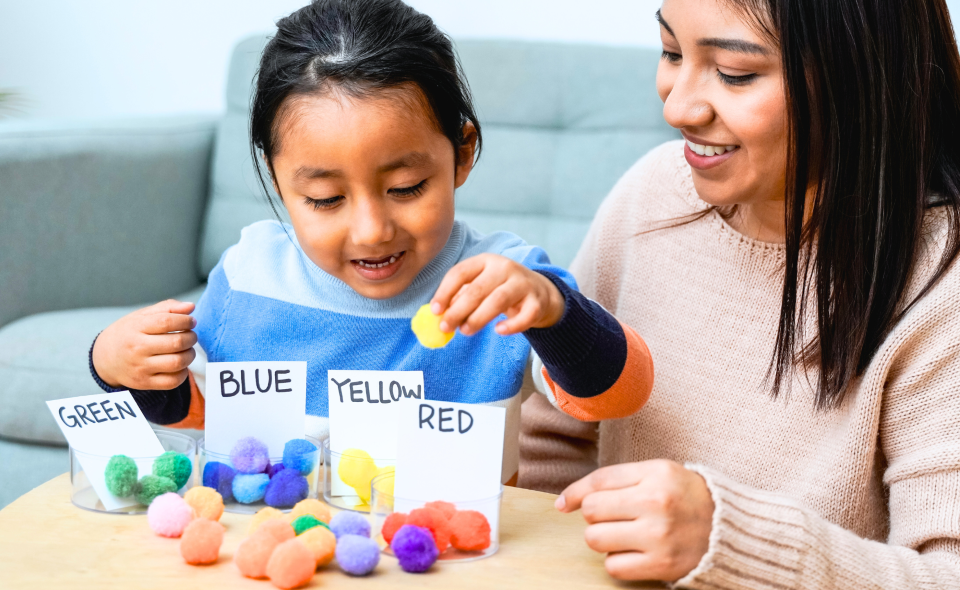 A mother watching her daughter play with toys that help detect developmental delays