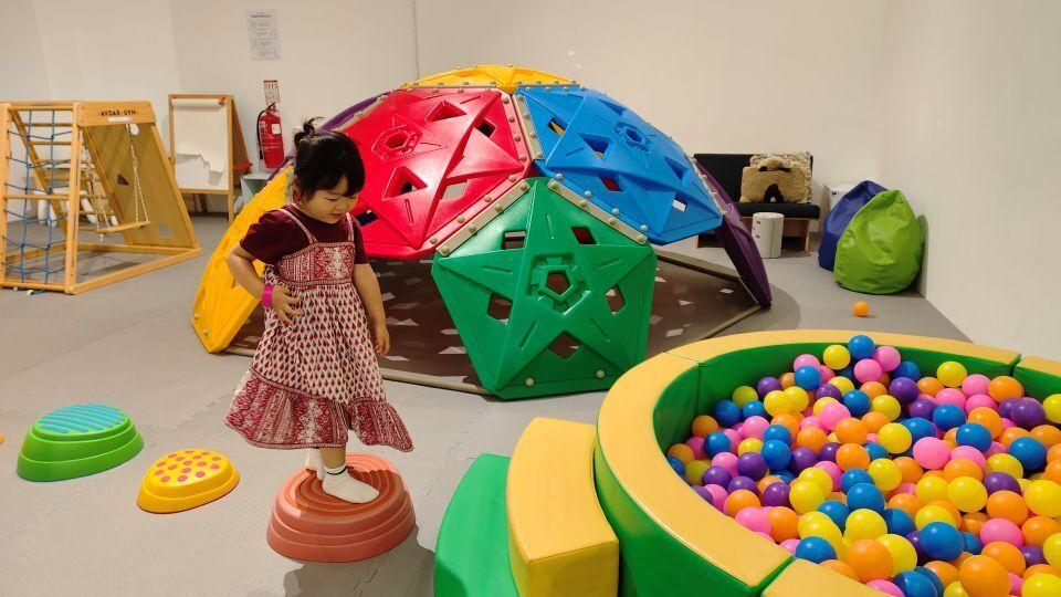 A screening location in a shopping mall, where a child is playing with a variety of colorful toys and apparatus