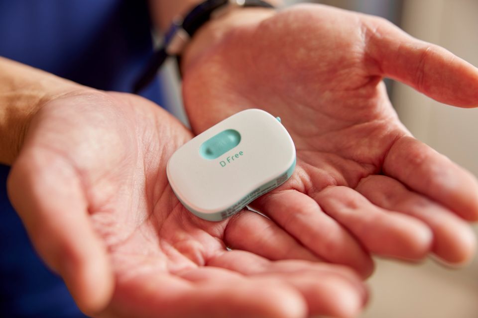 A personal holding a small,white Dfree device in both hands