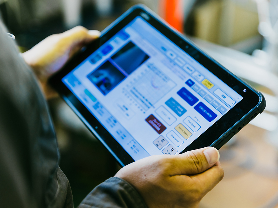 An operator holding a tablet to remotely control a repair robot