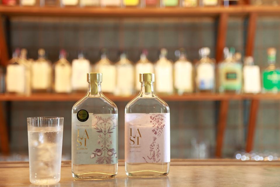 Two bottles and a glass of Ethical Spirits’ signature gin LAST, against a backdrop of other bottles