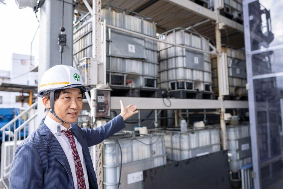A man in a hardhat showing an array of TOKYO8 culture tanks at the plant in Tokyo.