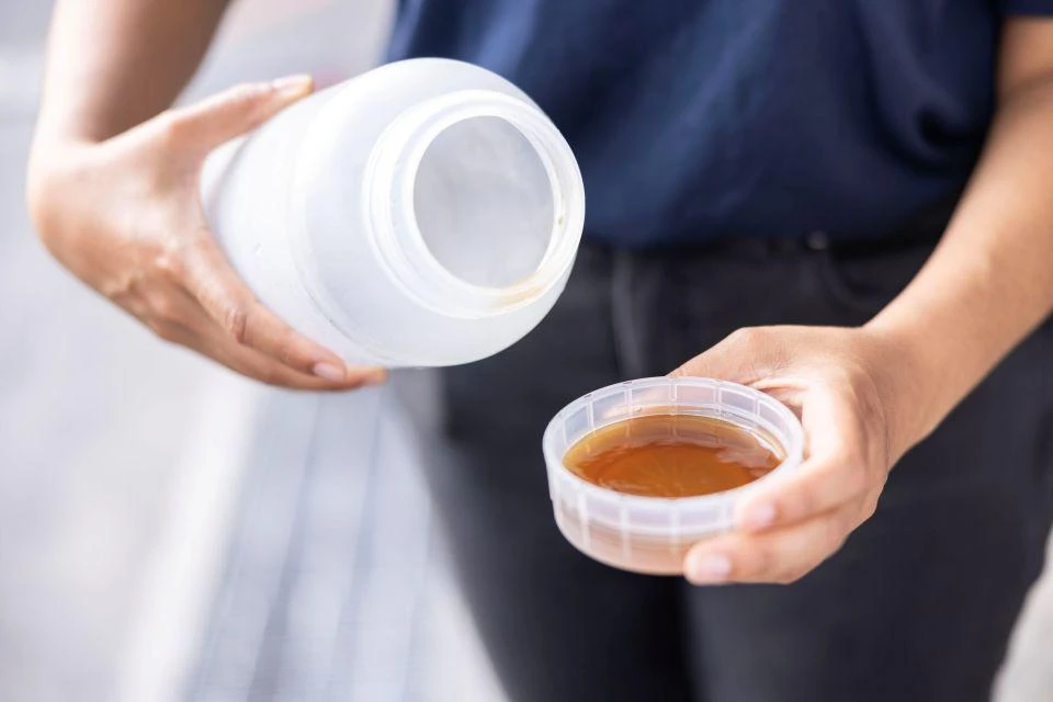 A person holding a capful of TOKYO8 in concentrated form.