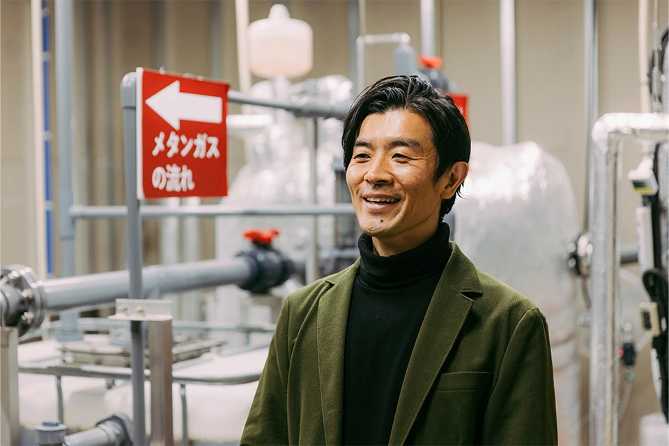 Baba Yasunori, President and CEO of Environmental Microorganism Research Institute Co., Ltd, posing in front of one of the company's methane fermentation systems 