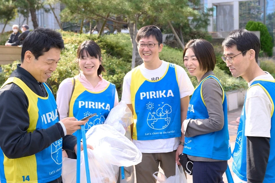 A group of people wearing blue and yellow shirts with the Pirika logo during a clean-up event