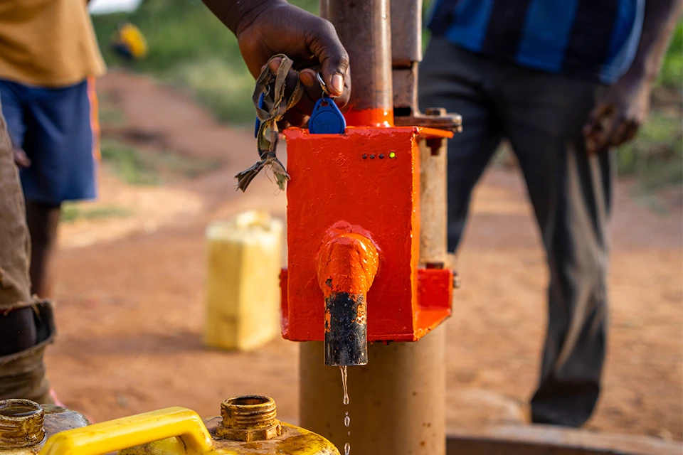 A person using a Sunda ID tag to get water from a pump